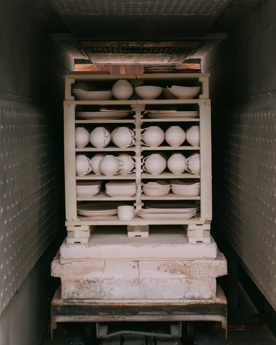 Interior de un horno cerámico cargado con vajilla sin esmaltar sobre placas refractarias y soportes